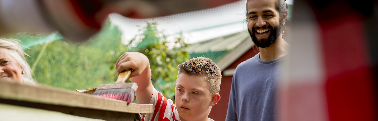 Inklusives Engagement: Studierender begleitet Kind mit Down-Syndrom beim Streichen – Master Soziale Arbeit & Management berufsbegleitend an der FHD Dresden