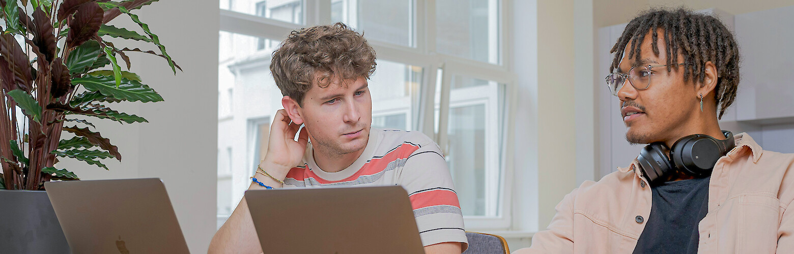 International students of the Dresden University of Applied Sciences in conversation while working together on laptops in a modern learning space