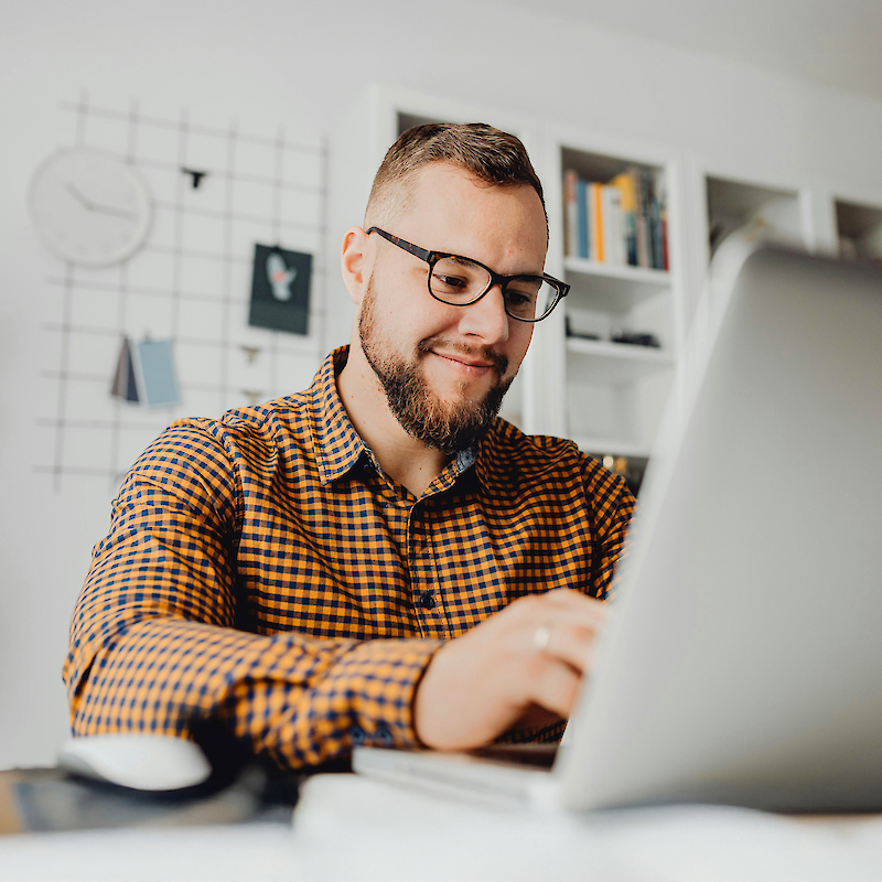 Mann mit Brille arbeitet am Laptop - ein berufsbegleitendes Studium an der Fachhochschule Dresden passt sich flexibel an dein Leben an.