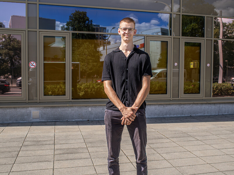 Absolvent Cedric aus dem Studiengang Tourismus & Event Management vor dem Gebäude der Fachhochschule Dresden.