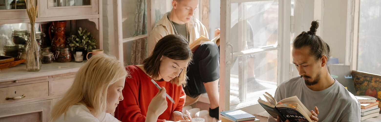 Studierende lernen gemeinsam in einer hellen WG-Küche, sitzen am Tisch mit Büchern und Notizen – typische Lernatmosphäre während der Prüfungsphase.
