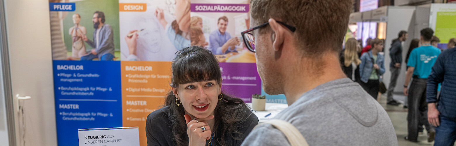FHD-Studienberatung im Gespräch mit einem Interessenten auf einer Messe